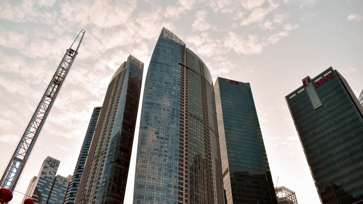 Conjunto de edifícios corporativos altos visto de baixo, com fachadas de vidro.